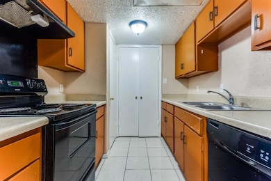 Kitchen with a textured ceiling, black appliances,