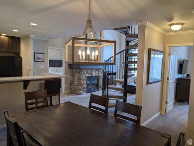 Dining space featuring ornamental molding, a stone fireplace, carpet floors, and a chandelier