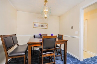 Carpeted dining room with baseboards and a chandelier