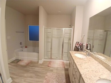 Bathroom featuring vanity, wood finished floors, a stall shower, and a garden tub