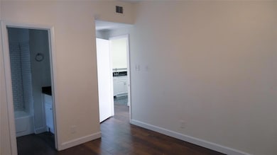 Unfurnished bedroom featuring connected bathroom and dark wood-style floors