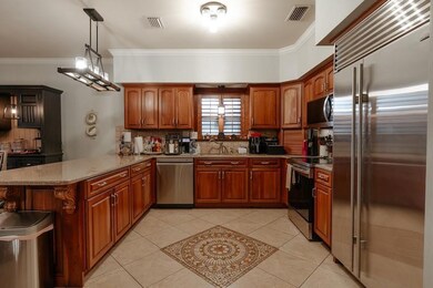 Kitchen featuring stainless steel appliances, ornamental molding, backsplash, a peninsula, and brown cabinetry