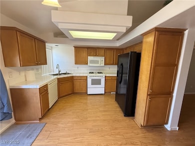 Kitchen featuring white appliances, a sink, light