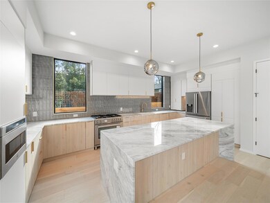 Kitchen featuring light brown cabinets, a center island, modern cabinets, light stone countertops, and recessed lighting
