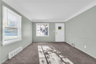 Entryway featuring carpet, wooden walls, and a wainscoted wall