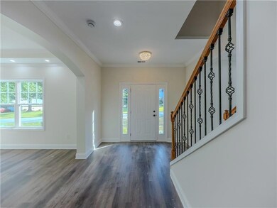 Foyer featuring arched walkways, wood finished floors, stairway, ornamental molding, and recessed lighting