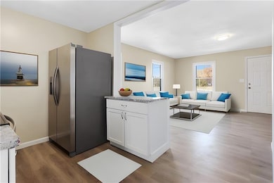 Virtual Staging Kitchen with stainless steel fridge with ice dispenser, dark wood-type flooring, white cabinetry, light stone countertops, and open floor plan
