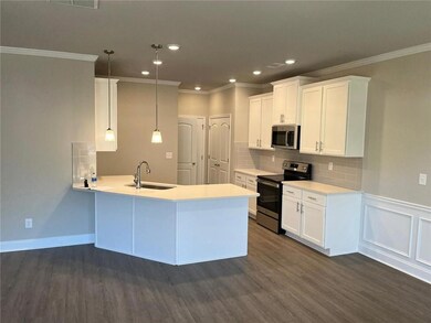 Kitchen with stainless steel appliances, dark wood finished flooring, white cabinetry, and recessed lighting.