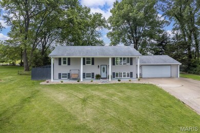 Split foyer home with driveway, a front lawn, an attached garage, and covered porch