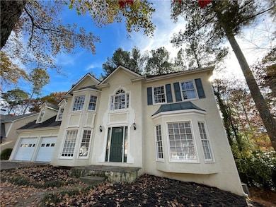 View of front facade featuring stucco siding, driveway, a standing seam roof, and a garage