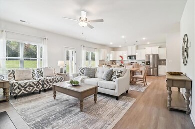 Living room with ceiling fan and light hardwood / 