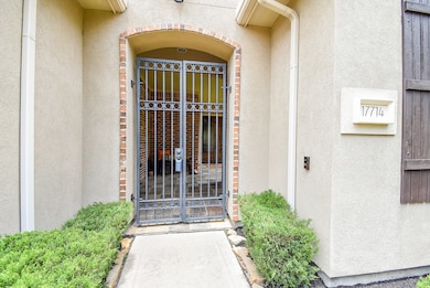 Wrought iron gate leads to the shaded front porch