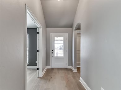 Doorway featuring vaulted ceiling and light hardwo