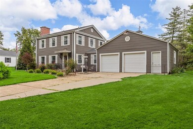 View of front of property with a chimney, a front yard, and driveway
