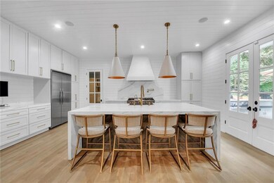 Kitchen with built in refrigerator, light wood finished floors, french doors, white cabinets, and a breakfast bar area
