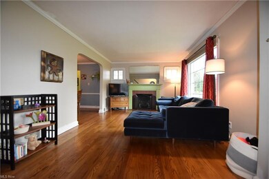 Living room with crown molding, light hardwood flo