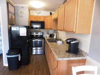 Kitchen featuring black appliances, dark wood-style flooring, light countertops, light brown cabinetry, and tasteful backsplash