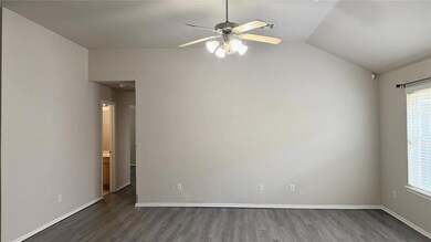 Spare room with wood finished floors, vaulted ceiling, and ceiling fan