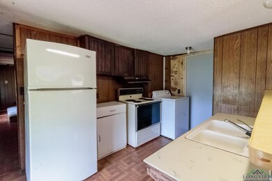 Kitchen featuring white appliances, washer / dryer, a sink, a textured ceiling, and light countertops