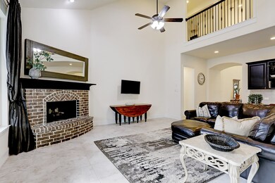 The Family room features a raised hearth fireplace with mantel, 18 inch neutral tile floor, soaring tall ceiling, and recessed lighting.