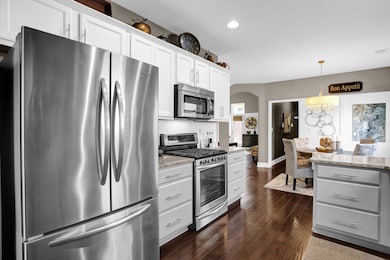 Kitchen featuring light stone counters, stainless steel appliances, dark wood flooring, and subway tile backsplash