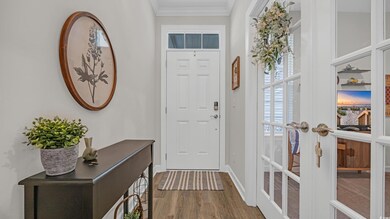 Entryway with wood finished floors, ornamental molding, baseboards, and french doors
