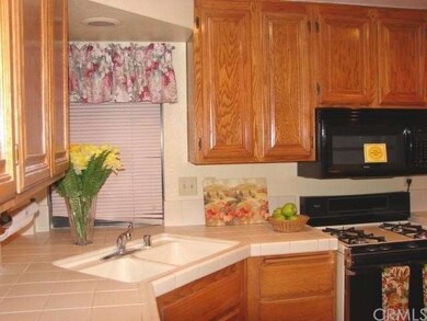 VIEW OF KITCHEN WITH TILED COUNTERS AND GAS STOVE,
