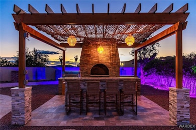 Patio terrace at dusk with a pergola, a fireplace,