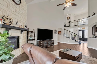 Living room with arched walkways, dark wood-style floors, stairs, and high vaulted ceiling