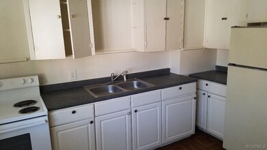 Kitchen featuring sink, white cabinets, and white appliances
