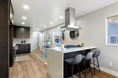Kitchen with a kitchen bar, light wood finished floors, a peninsula, tasteful backsplash, and recessed lighting