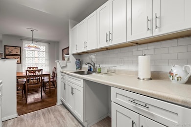 Kitchen featuring a sink, light countertops, light wood-style flooring, and white cabinetry