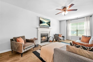 Living area with a warm lit fireplace, ceiling fan