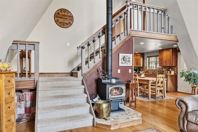 Stairway with wood finished floors, a wood stove, and a high ceiling