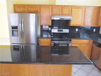 Kitchen with stainless steel appliances, dark stone countertops, light tile patterned flooring, and tasteful backsplash