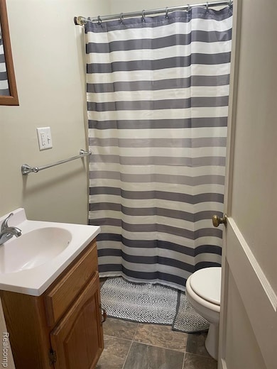 Full bathroom with vanity, a shower with shower curtain, and dark stone finish floors