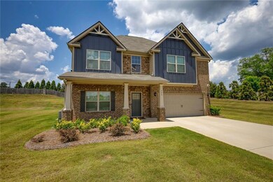 Craftsman-style home with board and batten siding, an attached garage, driveway, and brick siding