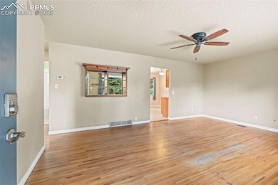 Unfurnished room with ceiling fan, light wood-type flooring, and a textured ceiling