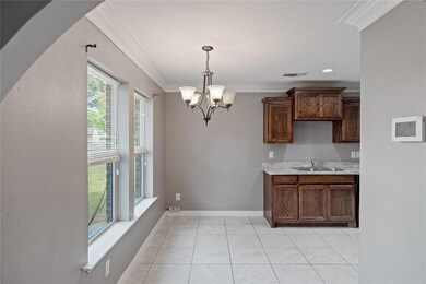 Kitchen with light tile patterned floors, an inviting chandelier, sink, pendant lighting, and ornamental molding