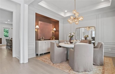 Dining space featuring a chandelier, a decorative wall, light wood-style floors, recessed lighting, and crown molding