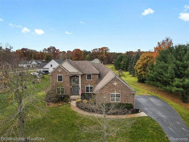 Traditional-style house with a front lawn, asphalt driveway, and brick siding