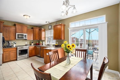 Kitchen featuring dark stone counters, brown cabinetry, light tile patterned flooring, stainless steel appliances, and decorative light fixtures