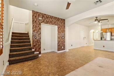Unfurnished living room with ceiling fan, stairway, and arched walkways