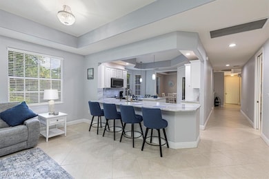 Kitchen featuring white cabinetry, a kitchen bar, pendant lighting, light tile patterned flooring, and a peninsula
