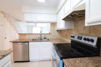Kitchen with under cabinet range hood, a sink, whi
