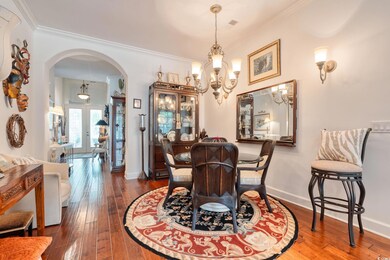 Dining room featuring arched walkways, a chandelier, crown molding, wood-type flooring, and french doors