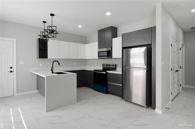 Kitchen with pendant lighting, sink, appliances with stainless steel finishes, white cabinetry, and kitchen peninsula