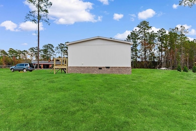 View of side of property with crawl space, a lawn, and a wooden deck