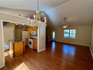 Kitchen with white appliances, a ceiling fan, open floor plan, light wood finished floors, and pendant lighting