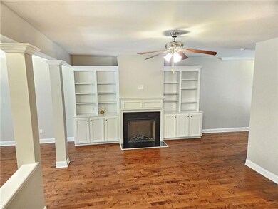 Unfurnished living room with a ceiling fan, a fireplace, wood finished floors, and baseboards